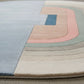 Close-up of a geometric patterned rug with pastel colors on a neutral background