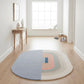 Round multicolored rug on a wooden floor in a bright room with a window.