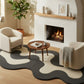 Modern living room with a fireplace, wavy patterned rug, and comfortable seating.