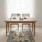 Wooden dining table with chairs in a bright room with white curtains.