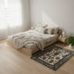 Modern bedroom with wooden bed, light bedding, and decorative rug.