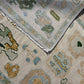 Close-up of a patterned rug with geometric designs in beige, green, and brown.