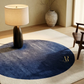 Round blue rug with a logo in a room with a lamp and vase.