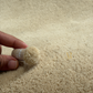 Person holding a small container of white powder on beige carpet