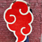 Person holding a red and white abstract rug against a brick wall