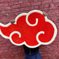 Red cloud-like symbol held by a person against a brick wall