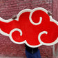 Red cloud symbol held by a person against a brick wall