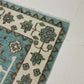 Close-up of two patterned rugs with floral designs on a light blue background.