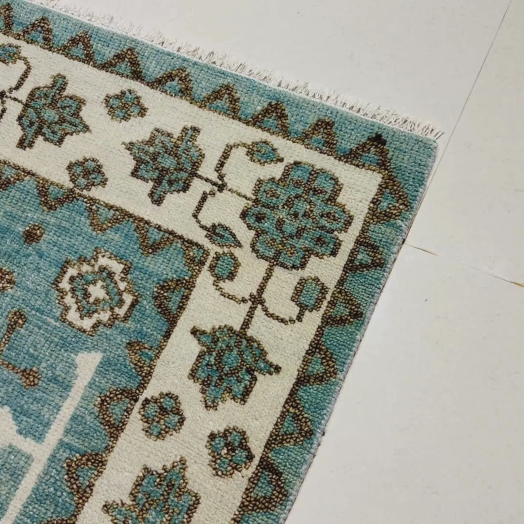 Close-up of two patterned rugs with floral designs on a light blue background.