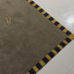 A green rug with yellow and black border in a room.