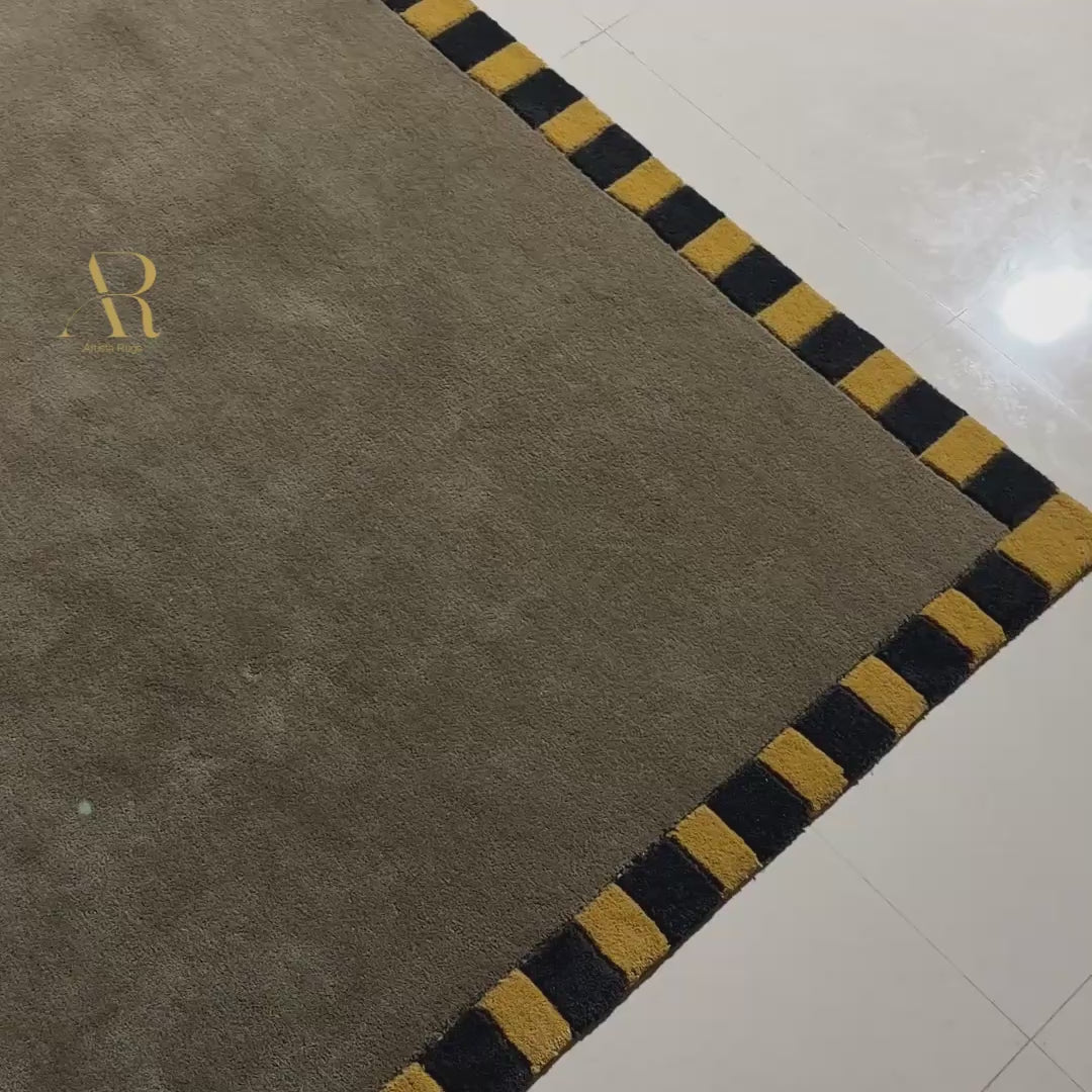 A green rug with yellow and black border in a room.