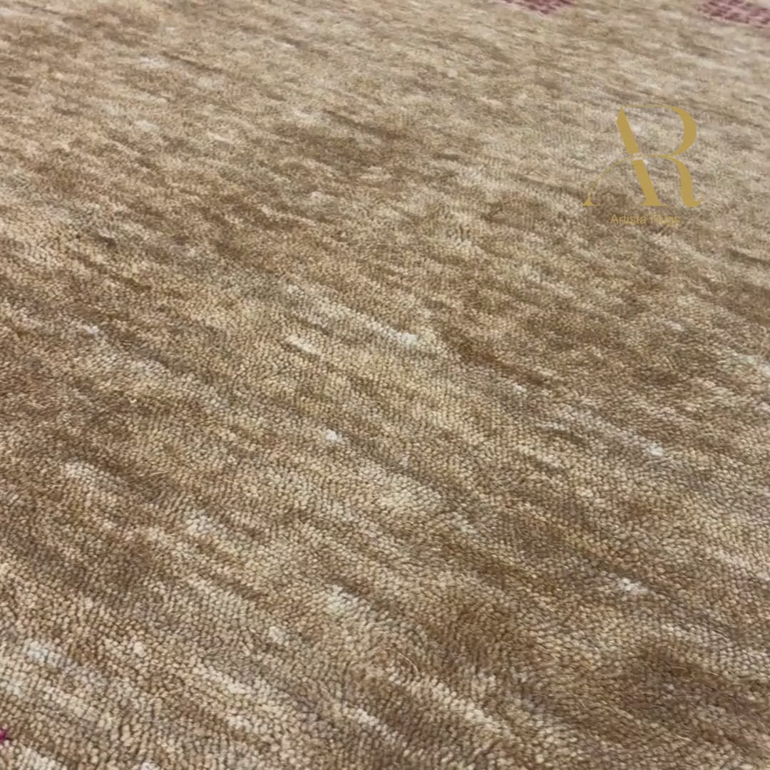 A rectangular brown area rug with a textured, heathered finish, featuring horizontal bands of small red geometric motifs and a central gold Om symbol near the bottom.